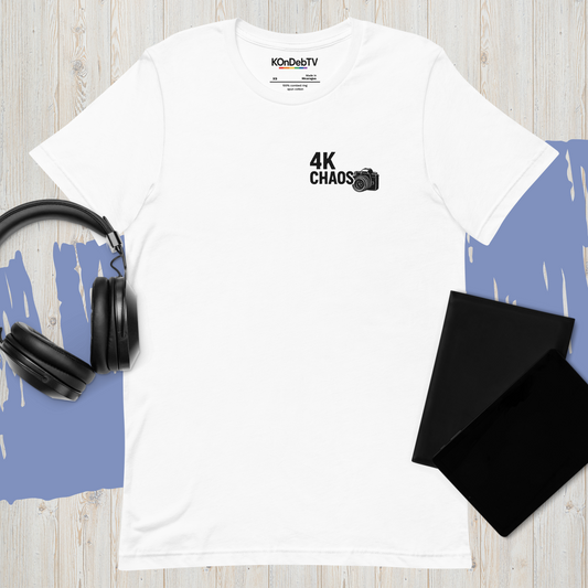 White unisex t-shirt laid on wood surface with bold black text reading "4KCHAOS." — styled with black headphones